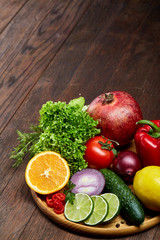 Still life of fresh organic vegetables on wooden plate over wooden background, selective focus, close-up