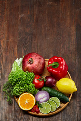 Still life of fresh organic vegetables on wooden plate over wooden background, selective focus, close-up