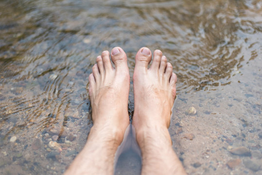 Close up Men's feet are soaked in streams river