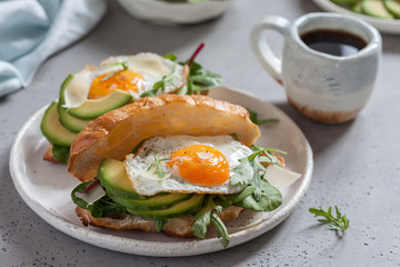 Breakfast with Croissant sandwiches with Fried Egg, Salad Leaves and avocado