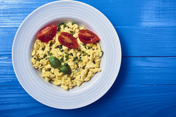 Scrambled eggs in plate on rustic background