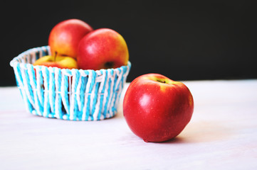 Red apples in a basket on a white wooden background