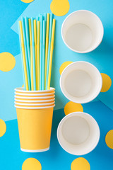 Yellow and blue straws for a party in paper cups on a bright background