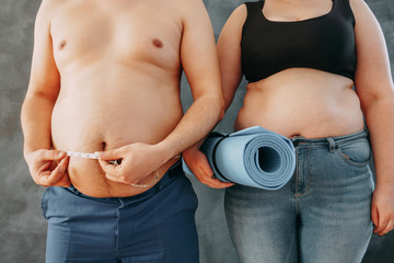 Overweight couple with measure tape and yoga exercise mat. Family weight losing