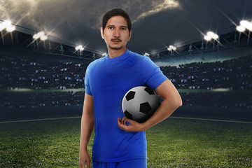 Handsome asian football player with soccer ball