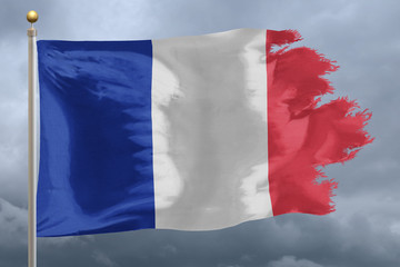 France Flag with torn edges in front of a stormy sky