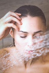 Young beautyful woman under shower in bathroom.