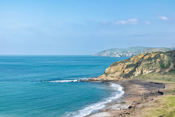 people walking along of wild beach with awesome cliffs along the coast