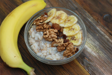 Top view of a Granola Bowl, Muesli with Oats, Nuts and Dried Fruit on Wooden table. Bannana, nuts, fruits. Healthy Breakfast. Diet.