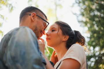 Fototapeta premium Beautiful young couple kiss and hug in a summer park near trees