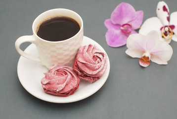 Sweet Pink Meringues and Cup of Coffee on Blue Gray background with Orchid Flowers. Spring Background with copy space. Breakfast.
