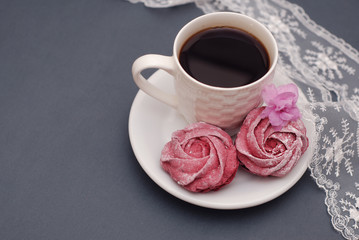 Sweet Pink Meringues and Cup of Coffee on Blue Gray background with Orchid Flowers and Lace. Spring Background with copy space. Breakfast.