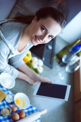 Beautiful woman cooking cake in kitchen standing near desk.