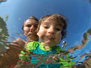 Underwater view of a father and her daughter with distorted faces having fun at the sea