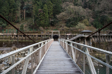 Narrow wooden bridge extends across a mountain river