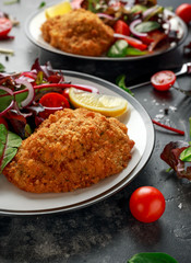 Breaded Chicken Kiev breast stuffed with butter, garlic and herbs served with vegetables in a plate.