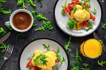 Eggs Benedict on english muffin with crispy bacon, wild rocket salad and hollandaise sauce.