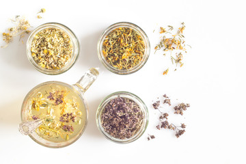 Curative herbs in glass jars on a white background
