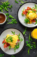 Eggs Benedict on english muffin with crispy bacon, wild rocket salad and hollandaise sauce.