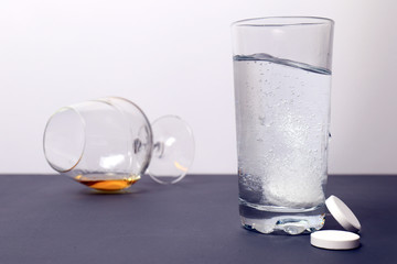 Concept of a hangover. Alcohol in the glass. Effervescent tablets against hangover to dissolve in a glass of water. Not a healthy lifestyle. Headaches

