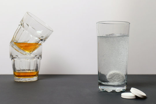 Concept of a hangover. Alcohol in the glass. Effervescent tablets against hangover to dissolve in a glass of water. Not a healthy lifestyle. Headaches
