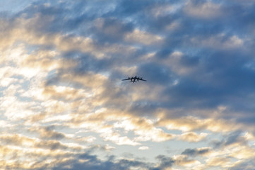 Silhouette of the plane in the clouds at sunset