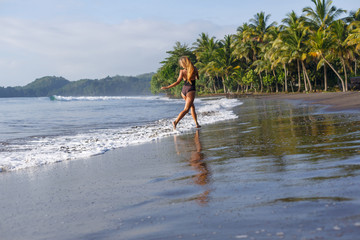 Back view of woman running on tropical beach near ocean