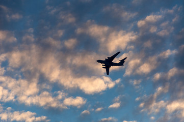 Silhouette of the plane in the clouds at sunset