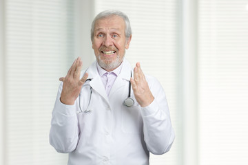 Emotional senior doctor gesturing. Excitied physician with raised hands up.