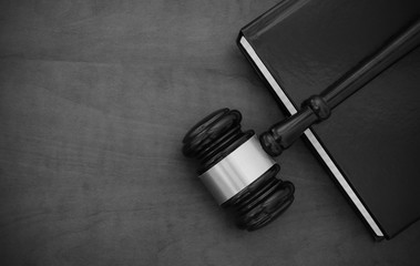 Wooden judge gavel and black legal book on wooden table