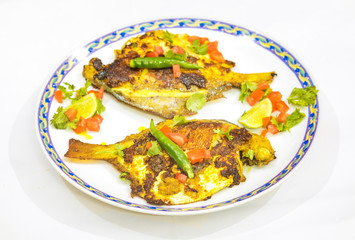 Crispy spicy fried pomfret fish garnished with vegetables. A popular Bengali Indian fish cuisine.