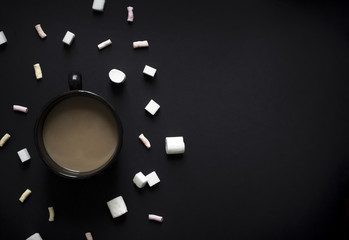 on a black dark background cup of black with coffee and milk marshmallows and sugar vignetting horizontal