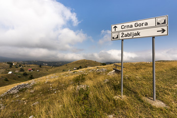 Lovely hilly landscape on a touristic road through Durmitor National Park in the Dinaric Alps with signposts to the villages 