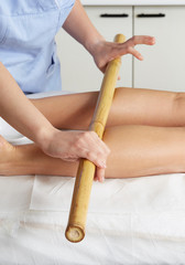 Woman having bamboo stick massage at day spa