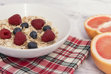 White bowl of muesli with raspberries, blueberries and grapefruit  
