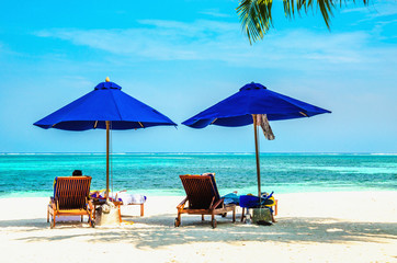 Blue umbrellas and wooden couches on a sandy beach