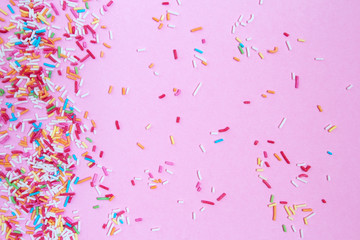 Multicolored confetti on a pink background top view