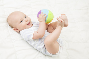 Baby Play Toy Ball, Happy Kid Lying on Back Playing Soft Toys, Infant Child Lie on White Blanket © inarik