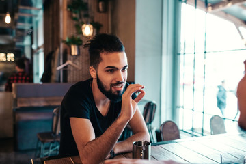 Happy arabian young men hanging in loft cafe. Friends talking in lounge bar by the window drinking...