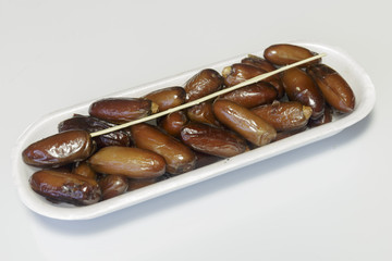 Dates, packed in plastic container, ready for sale, white background. Business concept. Close-up.