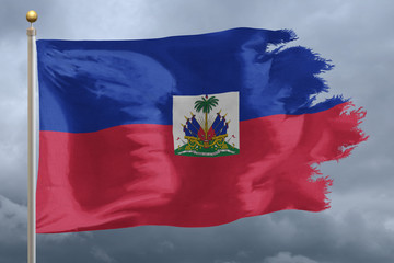 Fototapeta na wymiar Haiti Flag with torn edges in front of a stormy sky