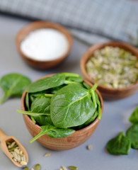 Fresh Spinach Leaves, Sea Salt and Seeds Nuts Mix in Wooden Bowl on Grey Background Healthy Food Concept Salad Ingredient 