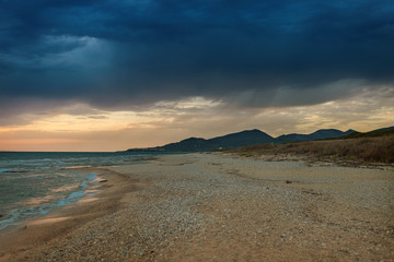 Fototapeta na wymiar The coast of the Greek island in stormy weather. It's raining on the horizon