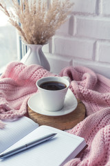 cup of coffee on a table in front of a window, the concept of breakfast and rest during work, a lifestyle of authentic, selective focus