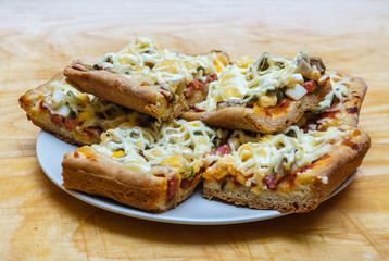 Plate with slices of homemade pizza with mushrooms and ham on wooden background