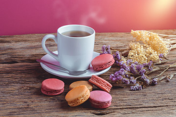 Different types color of macaroons with Cup of hot tea on Old grunge wooden background