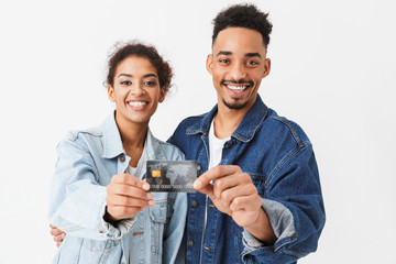 Happy african couple in denim shirts showing together credit card