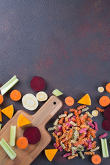 Kitchen background. Cooking delicious healthy food. Colorful dry pasta made from vegetables and its natural vegetable dyes celery, beet, carrot, pumpkin, parsnip.