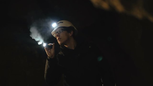 The speleologists with flashlight exploring the cave with fear