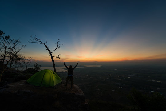 Traveler successful young man show hand standing on top of Mountain and waiting for sunrise.